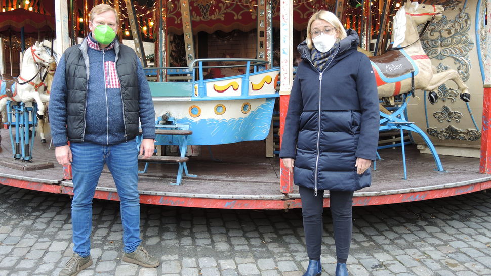 Bernhard Kracke und Katharina Pötter vor einem Kinderkarussell auf dem Weihnachtsmarkt