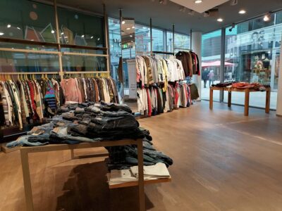 Gustav Pop-Up-Store: Kleidung auf Tischen und Kleiderbügeln im neuen Quartier. Jeans im Vordergrund.