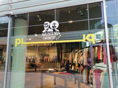 Schaufenster von GUSTAV, ein Pop-up-Quartier mit Vintage- und Designer-Kleidung. Kleiderständer im Hintergrund.