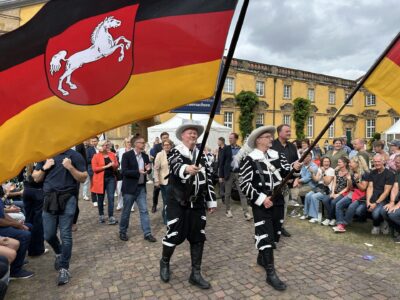 Spitze des Umzugs der Vielfalt zum Tag dert Niedersachsen 2025 IMG_6931.jpg: Festzug mit Trachtengruppe, Deutschlandflagge und Publikum. Traditionelles Event.