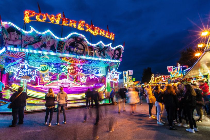 Herbst Jahrmarkt: Beleuchtetes Fahrgeschäft Power Express mit Menschenmenge.