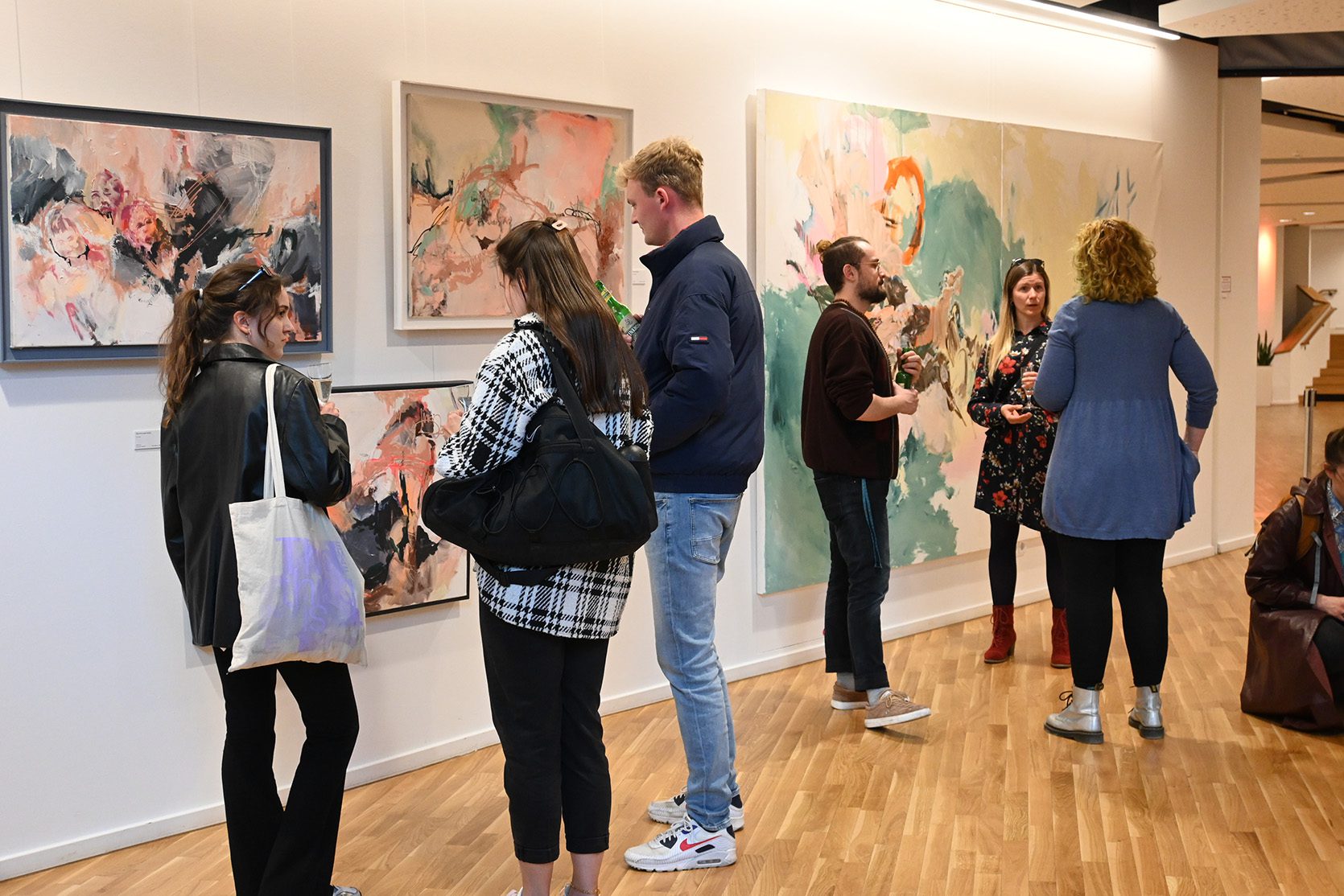 Besucher betrachten abstrakte Malerei von Inga Waldvogel bei einer Kunstausstellung im Foyer