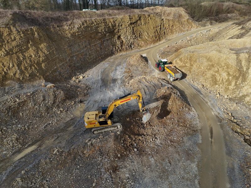 Arbeitsalltag 6 Bagger und Traktor mit Anhänger bewegen Erde in einer Kiesgrube