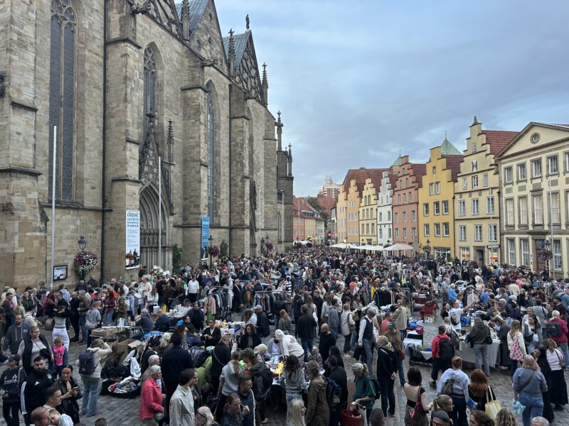 Menschenmenge auf dem Nachtflohmarkt vor historischer Kirche und bunten Giebelhäusern in der Altstadt